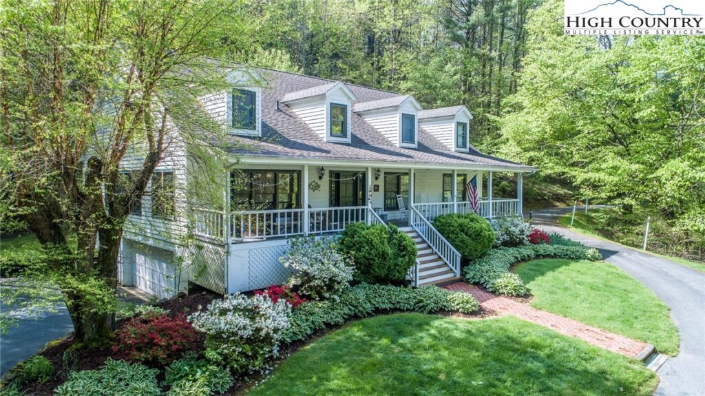 a stunning home surrounded by flower bushes and trees