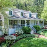 a stunning home surrounded by flower bushes and trees